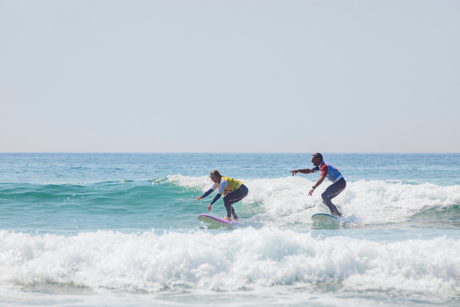 deux surfeurs sur une vague à lacanau pendant une séance de surf l'un des surfeurs pintes du doigts la direction de la vague