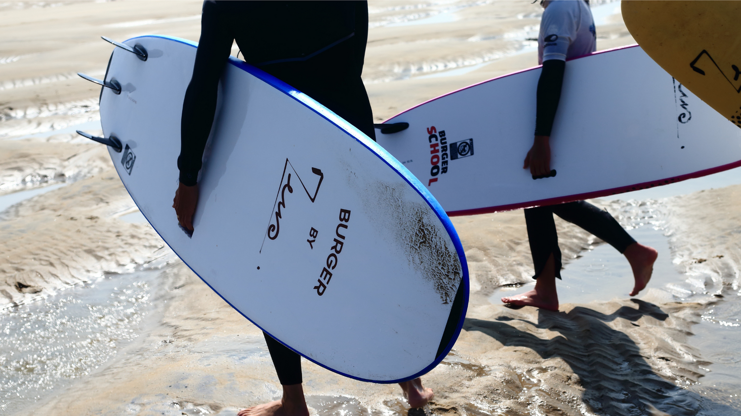 Surfers débutants portant leur équipement sur la plage pour aller surfer