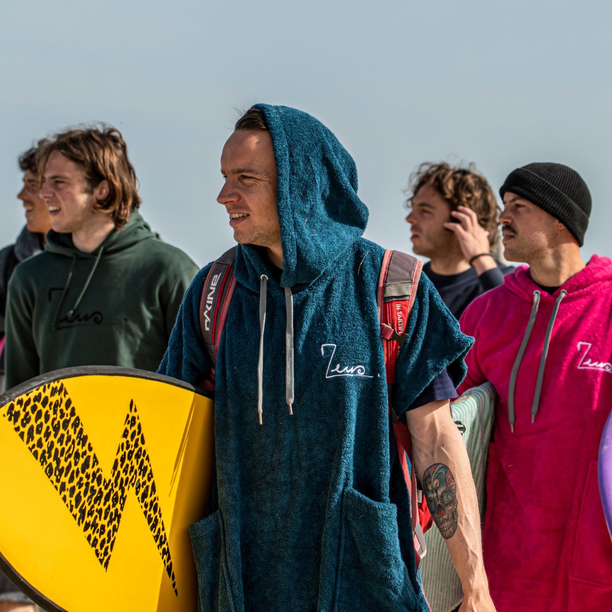 un groupe de surfeurs en avec des ponchos zeus 