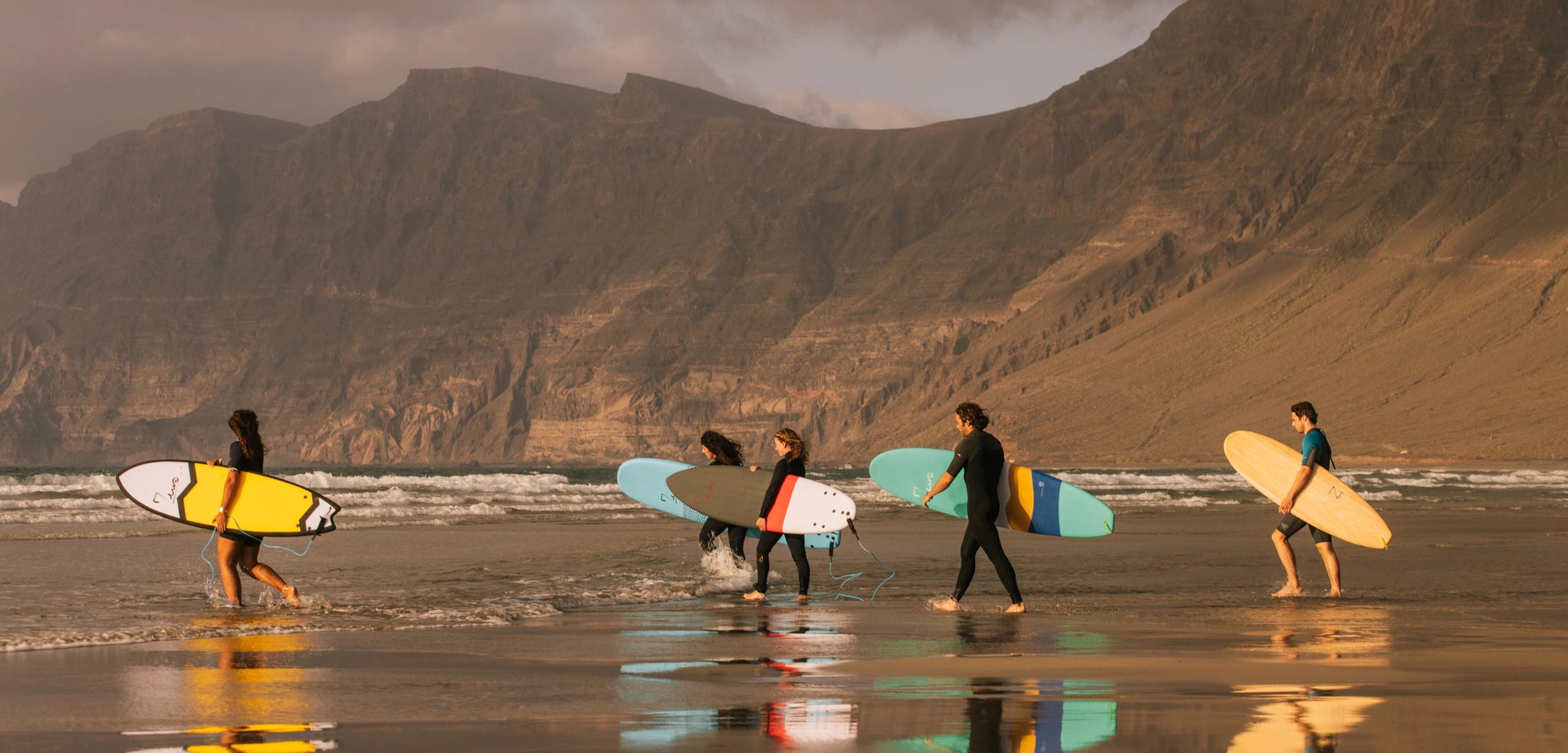 une bande de surfeur sur la plage de famara pendant un surfcamp zeus experience