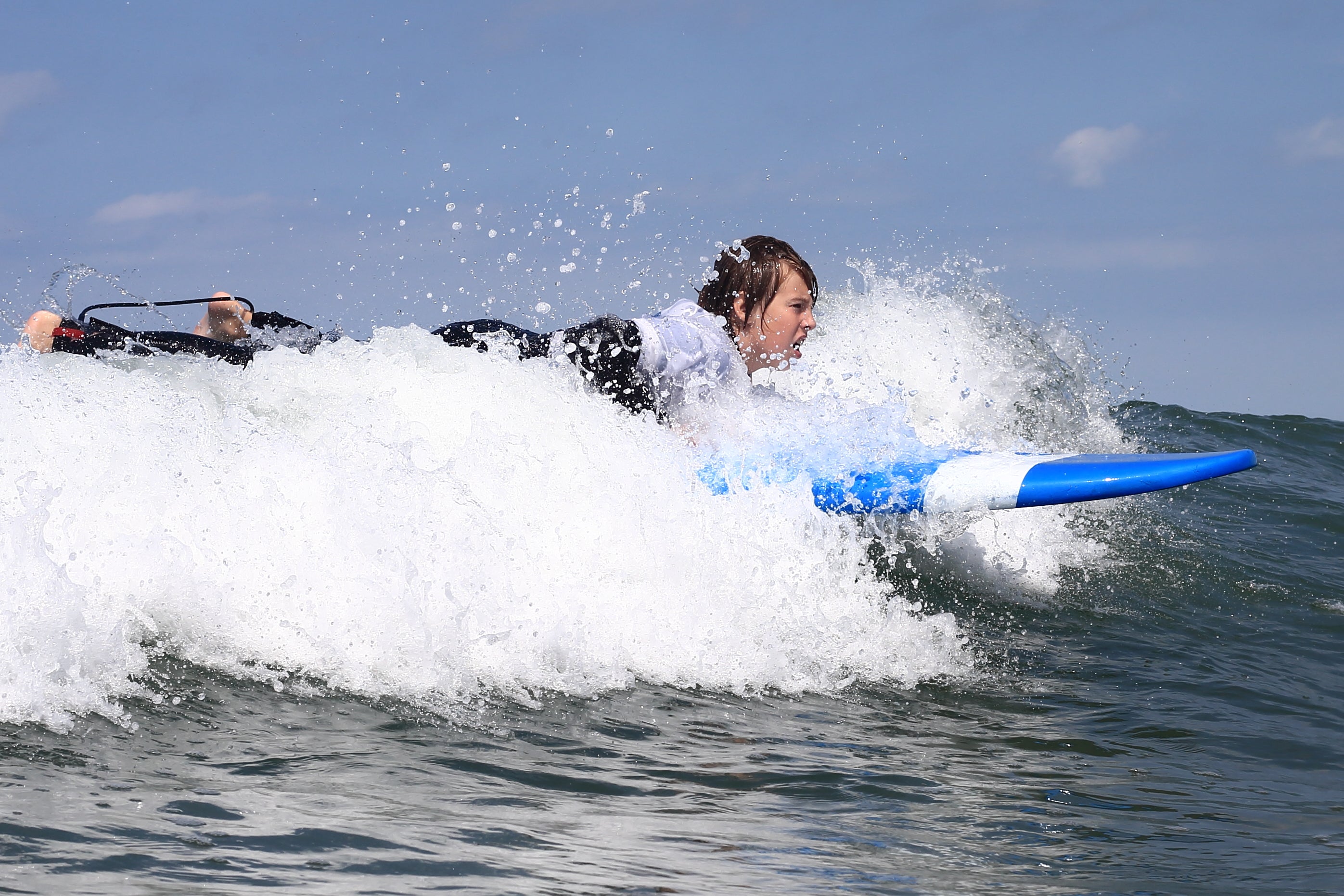 un enfant en train de commencer le surf en train d'essayer de faire un take off sur une mousse sur une planche de surf en mousse de softech bleu