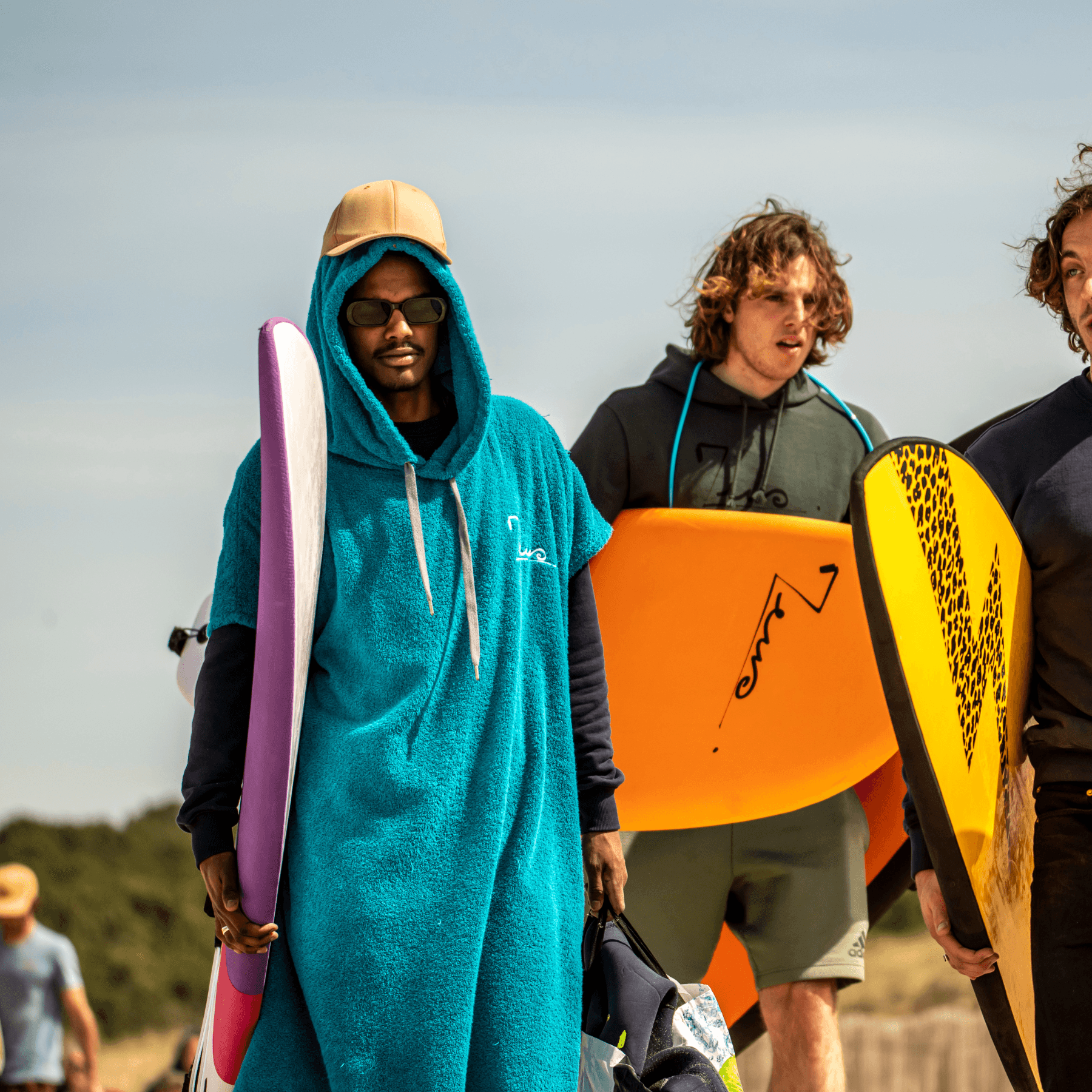 un surfeur qui porte sa planche de surf avec une poncho
