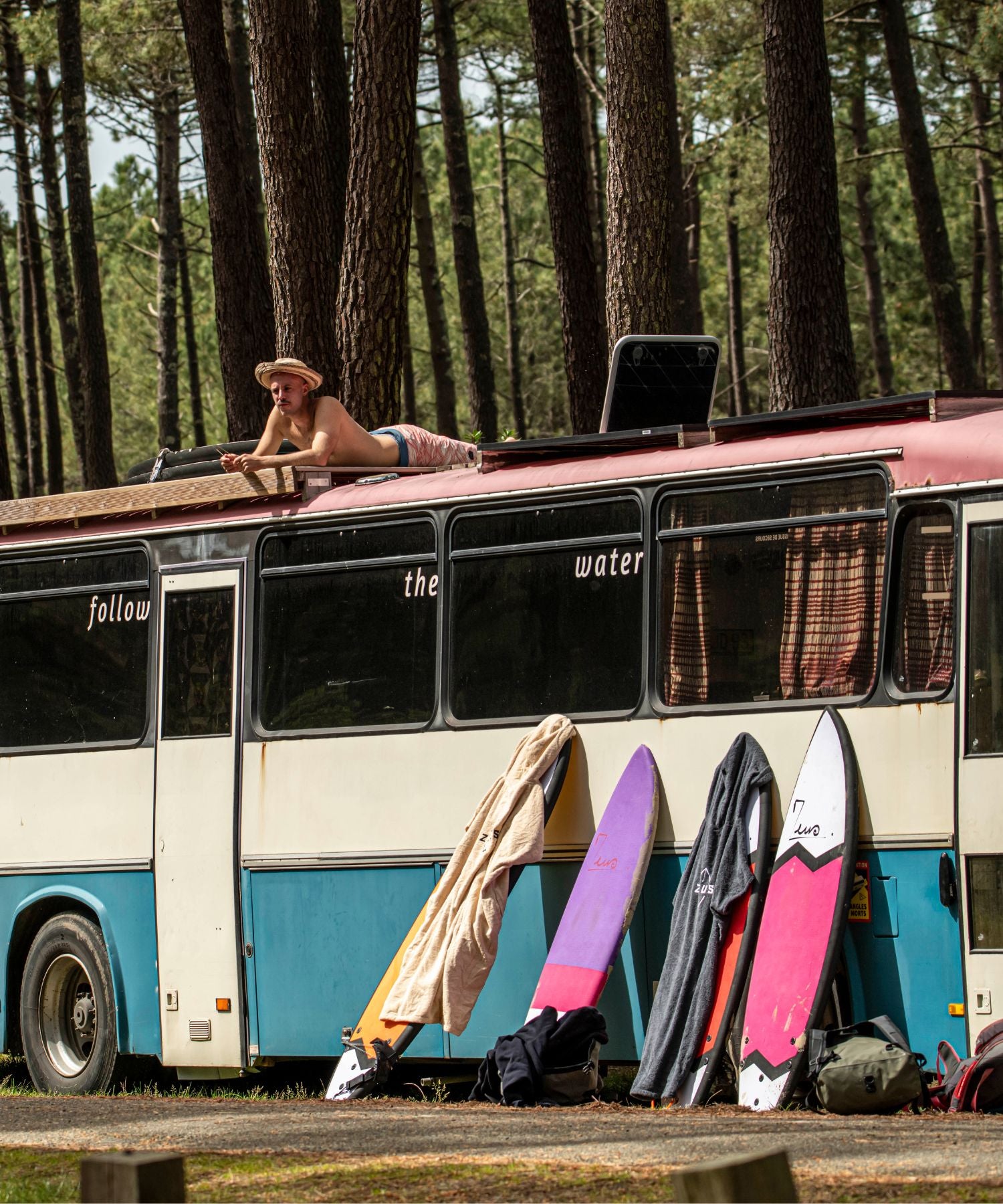 Un bus avec des planches de surf dans la forêt landaise
