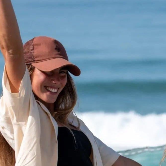 a woman in a hat waves to the camera