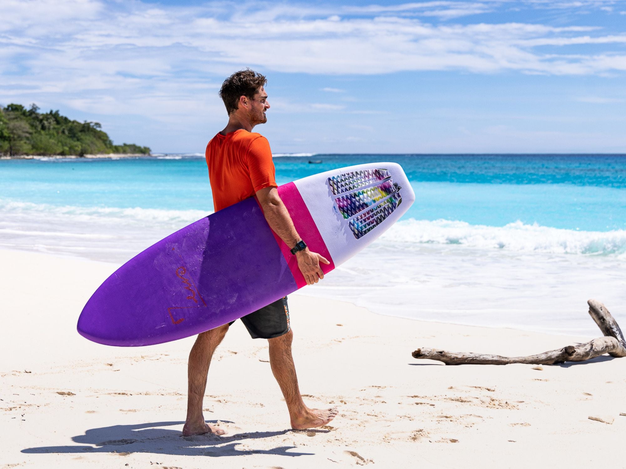 un sufeur sur une plage avec une planche de surf en mousse qui a de la wax sur le pont 