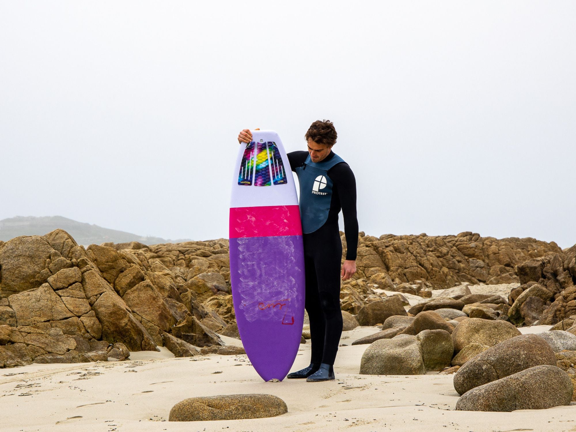 un surfeur avec une planche de surf en mousse dont le pont est recouvert de wax