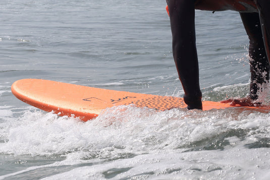 Planche de surf XXL Burger Zeus - Surfer à l'eau les mains sur la planche orange