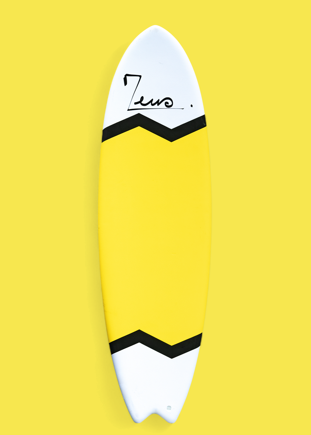 Planche de surf fish jaune et blanche vue de dessus sur fond jaune. Le design présente un color-block avec des sections blanches aux extrémités, séparées par des chevrons noirs en zigzag. La planche arbore le logo Zeus sur le nose et une queue swallow caractéristique