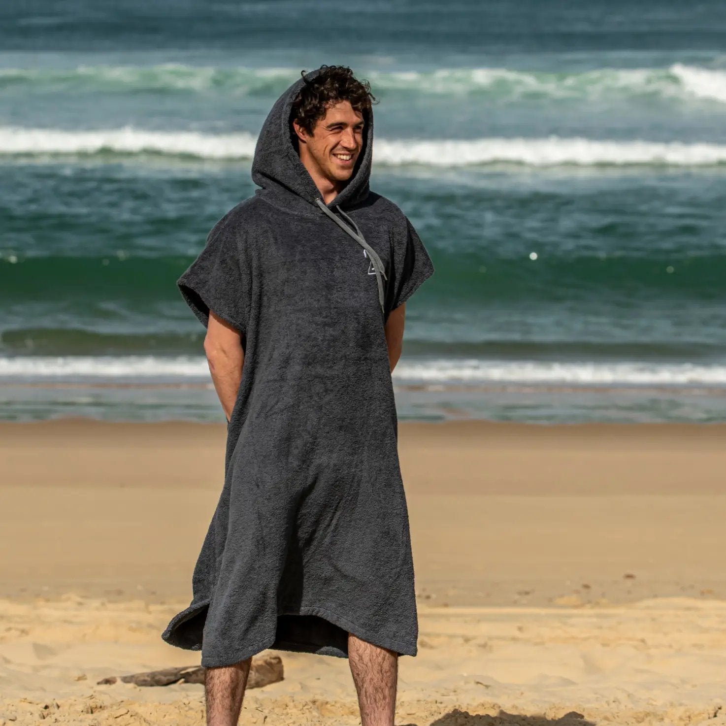a man standing on a beach wearing a hooded towel