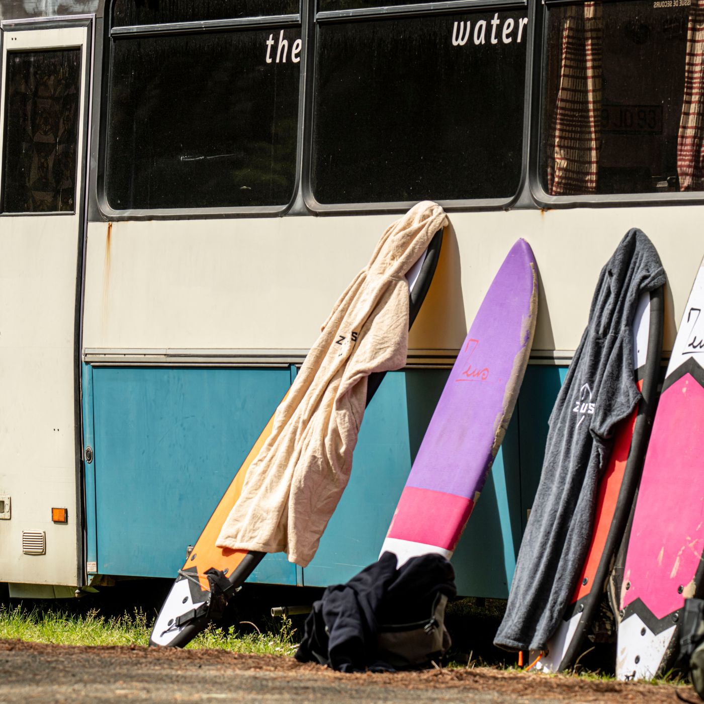 a group of surfboards leaning against the side of a bus