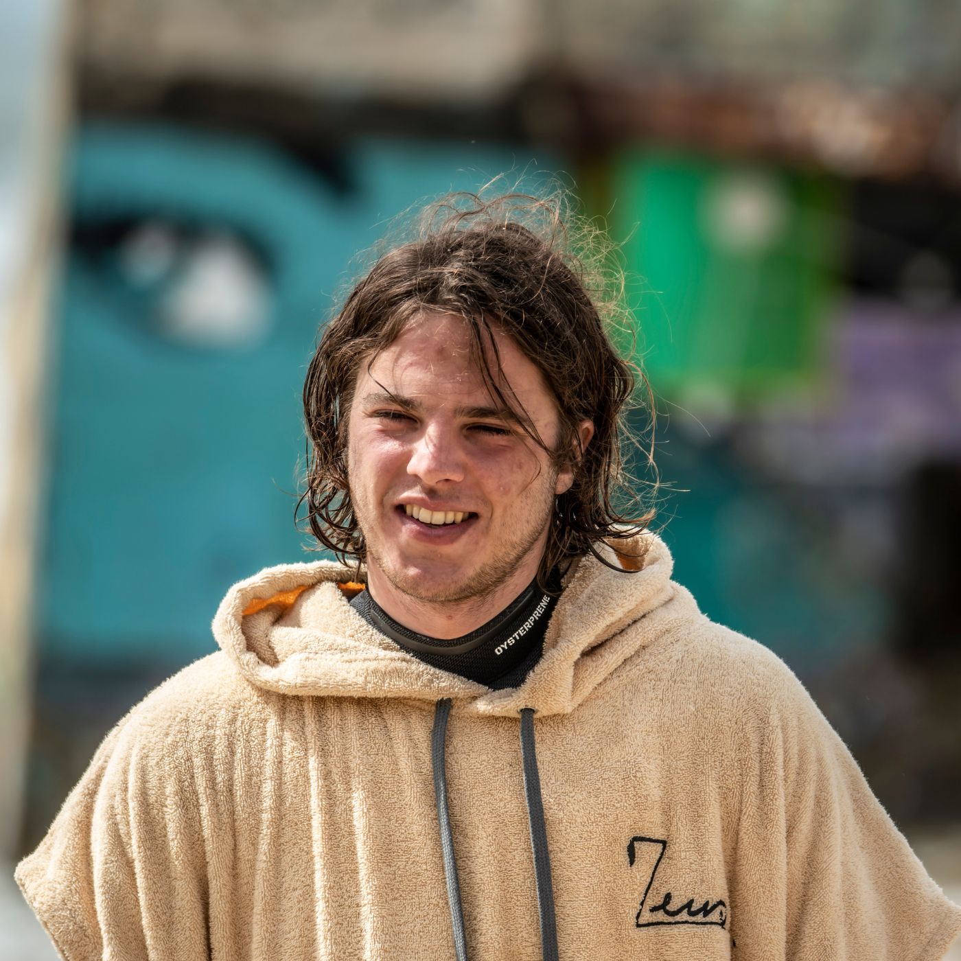 a man with long hair wearing a tan hoodie